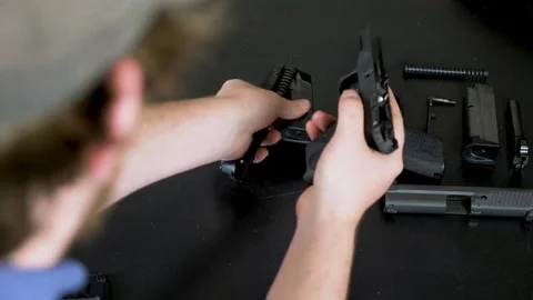 Man disassembles a handgun on a black table Stock Footage 76195870