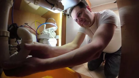 A man disassembles the plumbing under the sink for cleaning and maintenance. Stock Footage 270059070