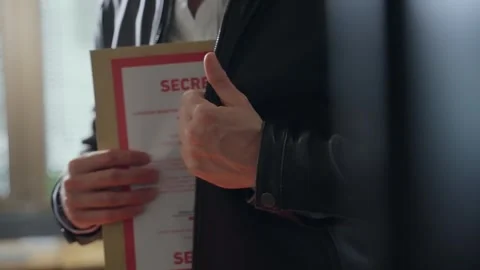 Man discreetly hides a secret folder inside his leather jacket, secrecy Stock Footage 304658828