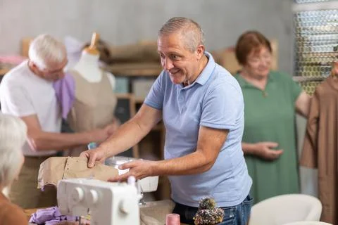 Man discussing pattern with female classmate during sewing course for older Stock Photos