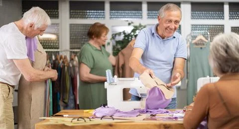 Man discussing pattern with female classmate during sewing course for older Stock Photos