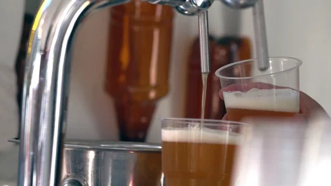 Man dispensing two glasses of beer from a machine Stock Footage 115077595