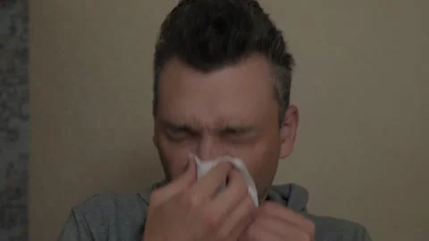 Man displaying cold symptoms in soft indoor lighting Vidéo 336555374