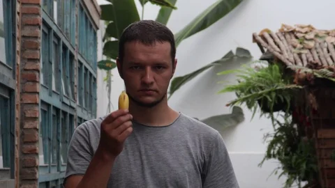 A man with a displeased face eats fruit. Stock Footage 119556148