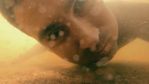 A man dives in and looks at an object at the bottom of the river in a funny way. Stock Footage 157921399
