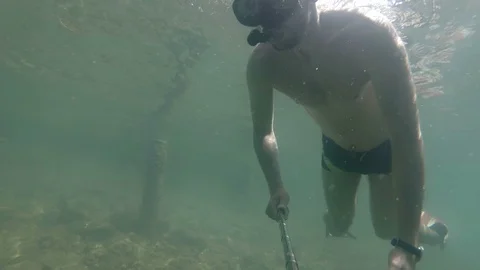 A man dives and makes a selfie under water. waving his hand to you 스톡 동영상 102012212