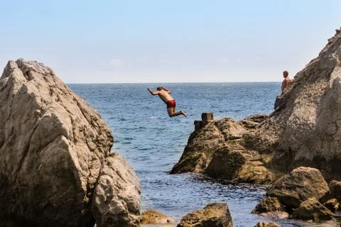 Man dives from the cliff. Stock Photos