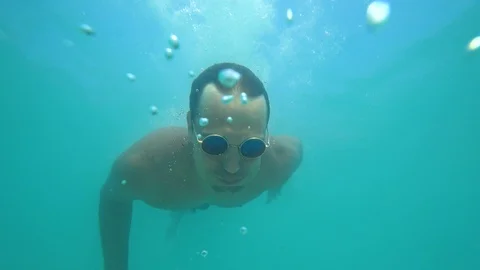 A man dives into a crystal clear sea  in sunglasses Stock Footage 87166201