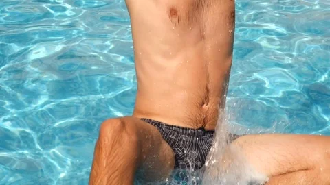 A man dives into the pool with blue water. Splashes fly in different directions Stock Footage