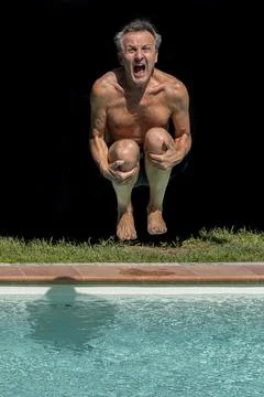 A man dives into the pool screaming, against a black background Stock Photos