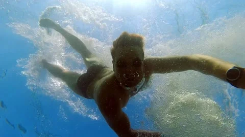 Man Diving and Looking at Camera seen from Underneath Underwater Slow Motion Stock Footage 220550791