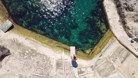 Man diving into crystal clear water from wooden pier in Cala s'Estaca Stock Footage 341515520