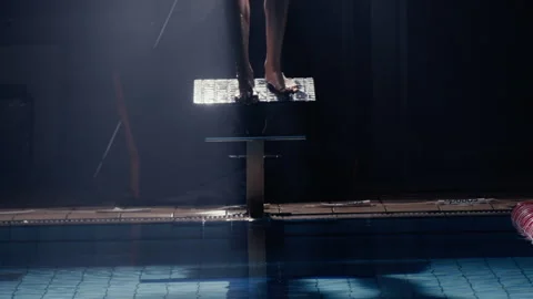 Man diving from a diving board into a swimming pool at night Stock Footage 275259546