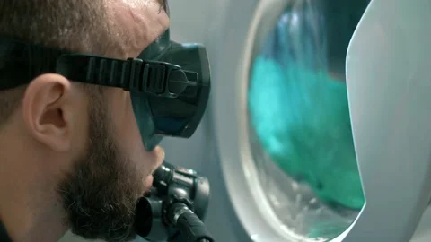 Man in diving gear looks into the hatch of a washing machine Stock Footage 151649801