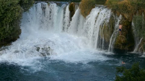 Man diving jumping in the water from the rock cliffs of a wild waterfall Stock Footage 90268030