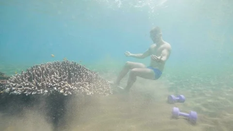 Man is diving in mask and sitting on seabed practicing apnea. Stock Footage 107140072