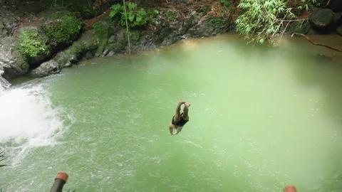 Man Diving Into Natural Pool at Waterfall in Slow Motion with Arms Extended. Stock Footage 338367853