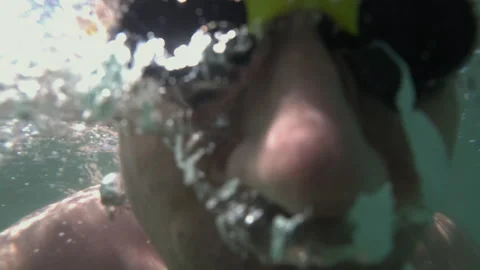 Man diving underwater with swimming goggles, sunlight glistening through the Stock Footage 339793475