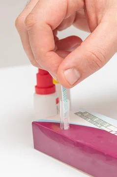 Man do portable streptococcus test analysis, patient dips test strip into fla Foto stock