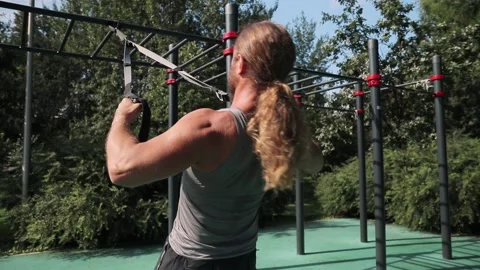 Man do reverse push-ups on playground among trees total body resistance exercise Video stock 139398217