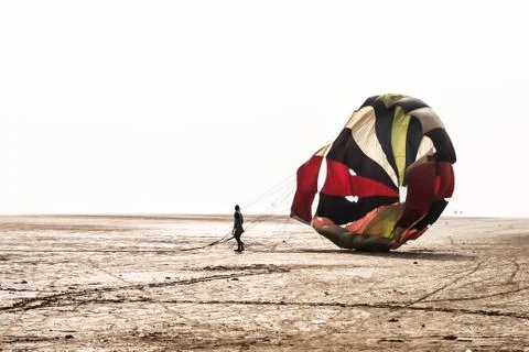 Man do some fold parachute after landing in a famous at Candolim Goa near Bag Fotos de archivo