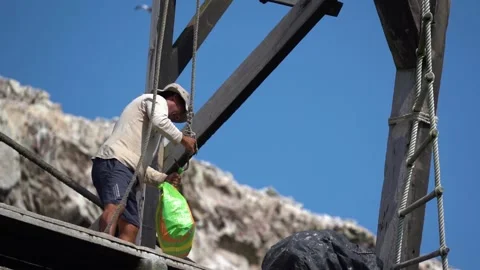 Man on dock in Peru taking off a plastic bag from a hook, Paracas coast, Stock-Footage 130761998