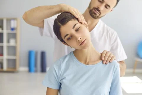 Man doctor chiropractor or osteopath setting womans neck joints with hands Stock Photos