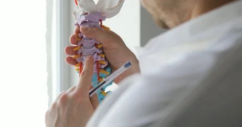 Man doctor is explaining the structure of the spine using spine model. Vídeos de archivo 108021459