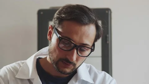 A man doctor in glasses writes in a diary while sitting at a table in his office Stock Footage 239608619