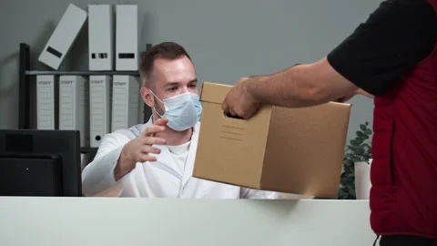 Man doctor wearing protective face mask, medical gown receiving delivery box and Stock Footage 162327261