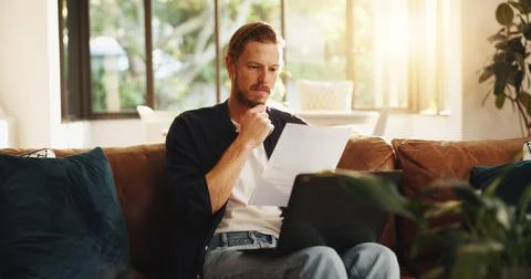 Man, document and reading on sofa with laptop, writer and thinking for script Stock Photos