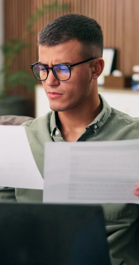 Man, documents and confused with remote work from home with laptop, glasses and Stock Footage 332887619