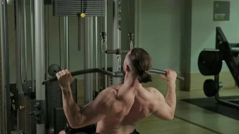 A man does a back exercise on a equipment. Gym training, sports Stock Footage 234326603
