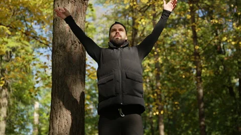 A man does breathing exercises in the park in autumn. yoga Stock Footage 220224791