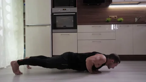 A man does an exercise - complicated push-ups from the floor at home. Stock Footage 130992965