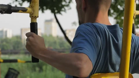 A man does an exercise for the pectoral muscles on a street sports simulator. Stock Footage 157845189