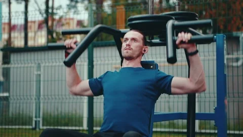 A man does exercises on the pectoral muscles, exercising in an open sports field Stock Footage 149754397
