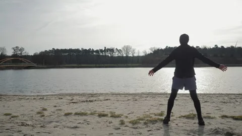 A man does exercises on the shore of the lake Stock Footage 265480752