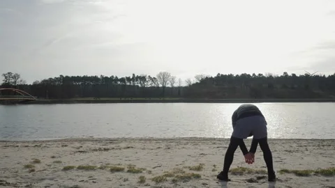 A man does exercises on the shore of the lake Stock Footage 265481855