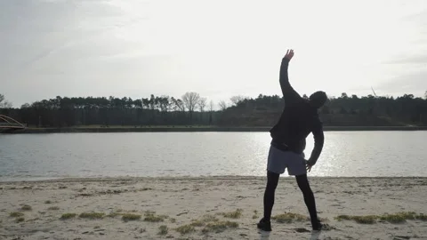 A man does exercises on the shore of the lake Stock-Footage 265681371