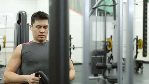 A man does exercises on the simulators in the gym. Exercise Press hands, sitting Stock Footage 240924110