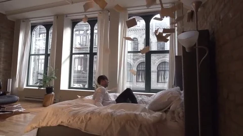 Man Does Flip onto Bed as Paper Pages Fall Stock Footage 82352807