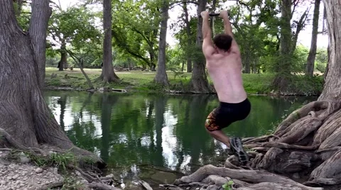 Man does a flip off a rope swing in lake Stock Footage 53340535