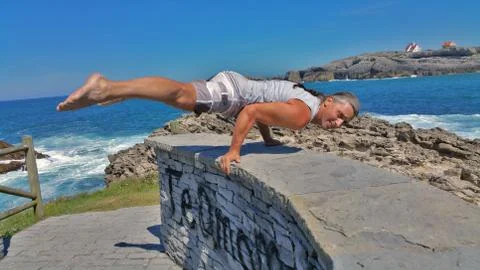 Man does gymnastic exercise on a stone wall Stock Photos