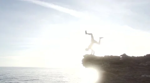 Man Does Hand Stand on Cliff with Amazing Sun Set Over Ocean Stock Footage 55298807