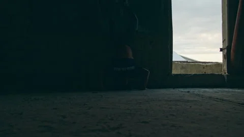 Man does handstand pushups in dark warehouse Stock Footage 275595217