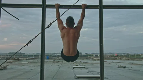 Man does hanging leg raise on rooftop exercise facility Stock Footage 275594573