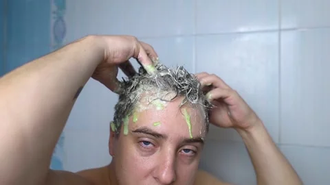 Man does head scrub. Dark-haired young man applies a scalp scrub to combat dandr Stock Footage 256218813