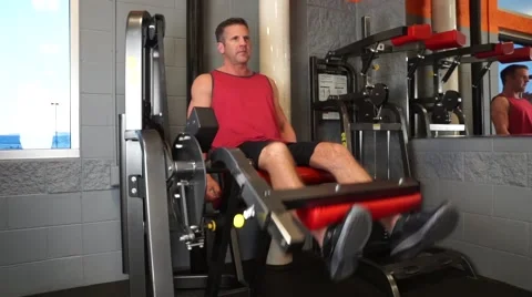 Man Does Leg Extensions At The Gym Vídeos de archivo 61576761
