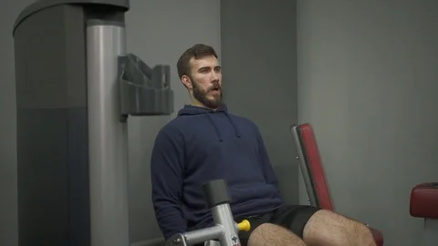 A man does leg lifts with a load on the exerciser for strengthening muscles. Stock Footage 129506929